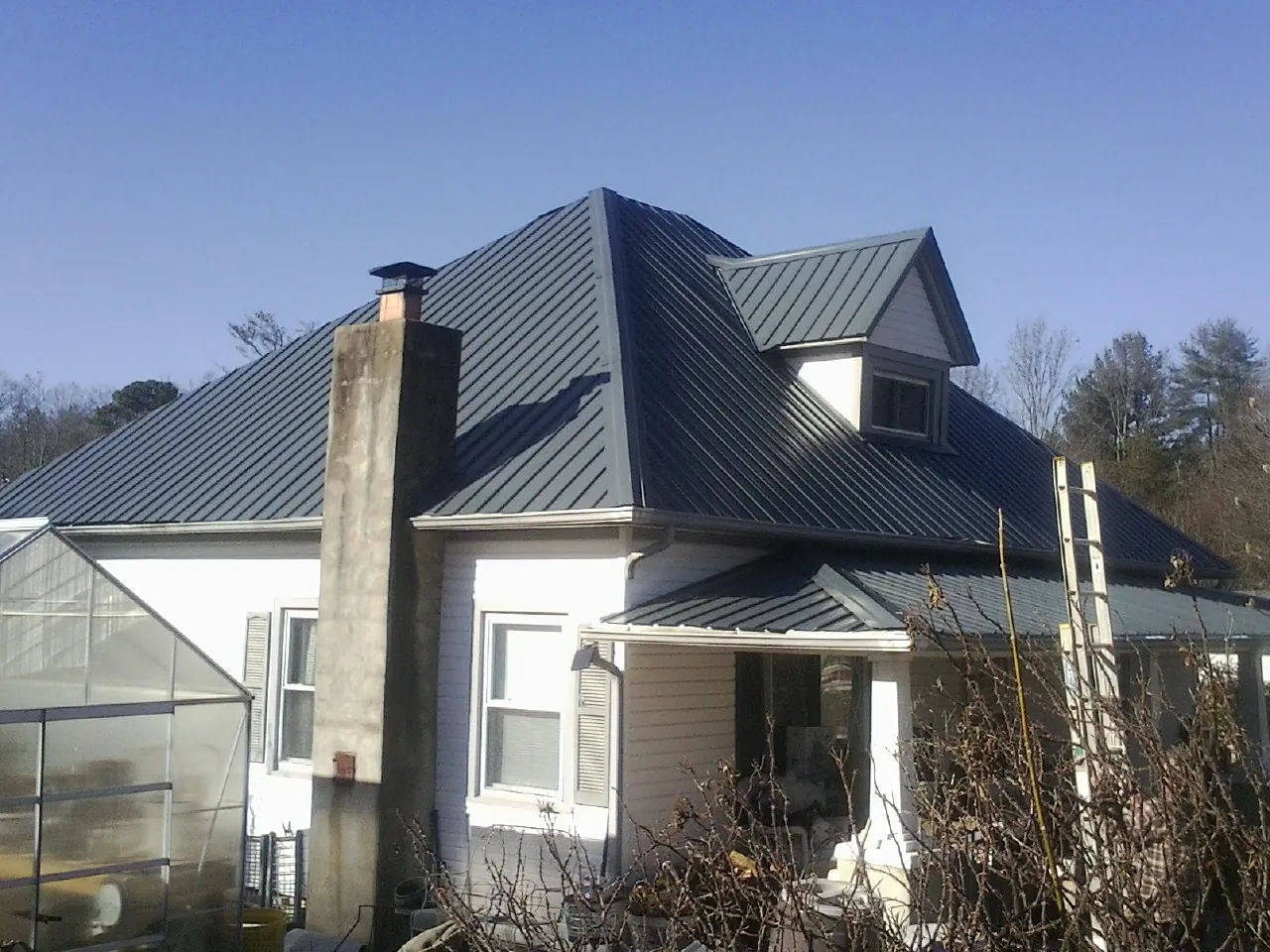 Dark blue standing seam metal roof on a white farmhouse with dormer — Slate & Tile Roof Repair by Roofing Brothers in Bern