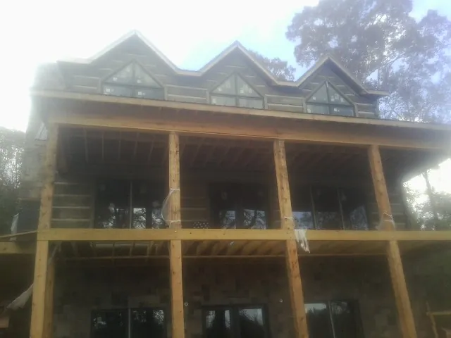 Dormers and porch framing on a large log home under construction — Roof Coating work by our crew in Bern