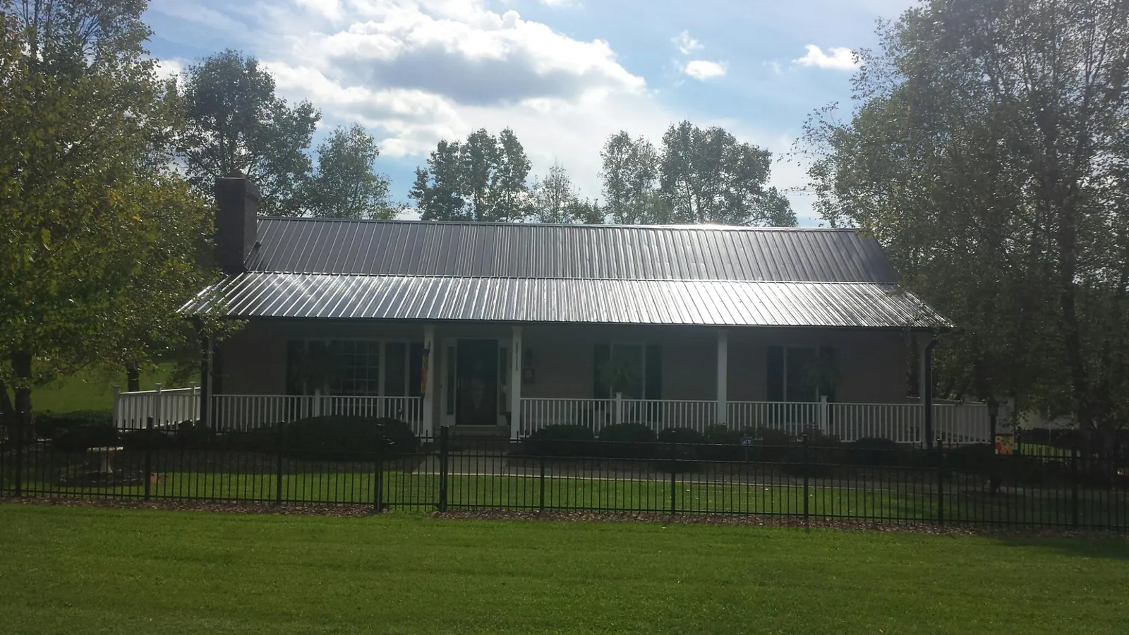 Gray metal roof on a brick ranch with a full width front porch — Gutter Guard Installation work by our crew in Bern