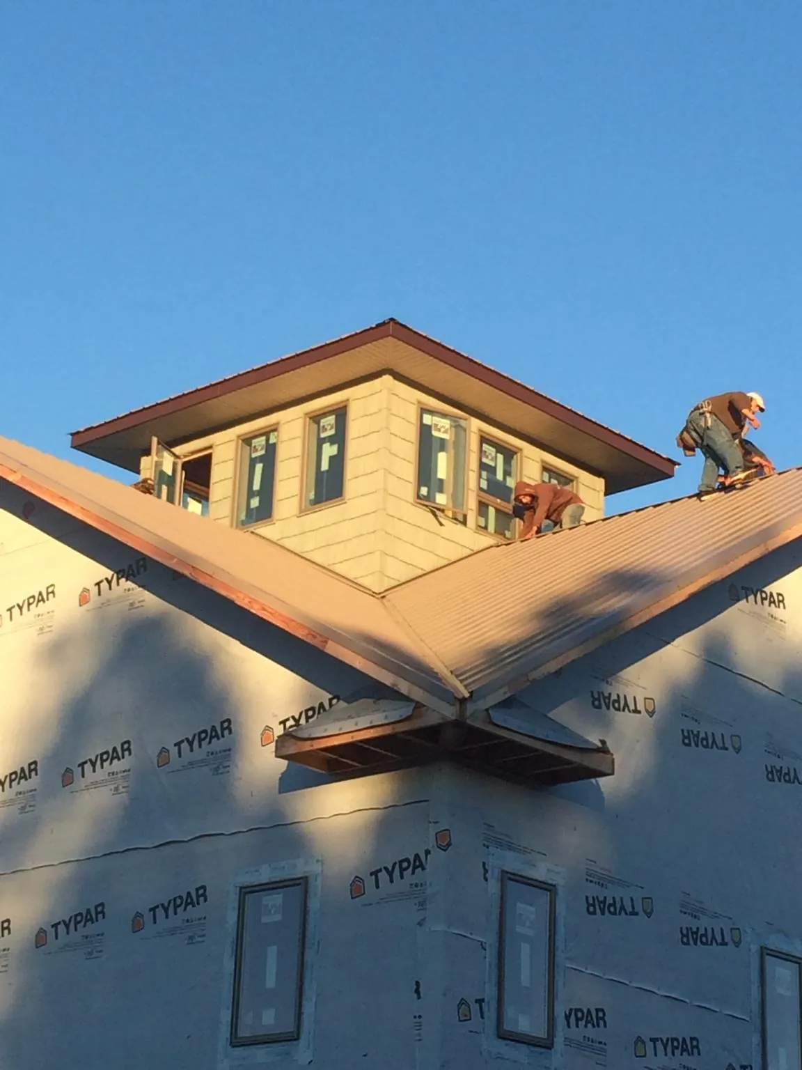 Roofers working around a rooftop cupola on a new metal roof at sunset — Roof Waterproofing in Bern by Roofing Brothers